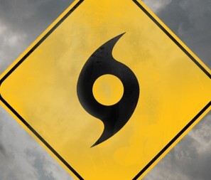 A yellow hurricane sign with grey storm clouds behind it.