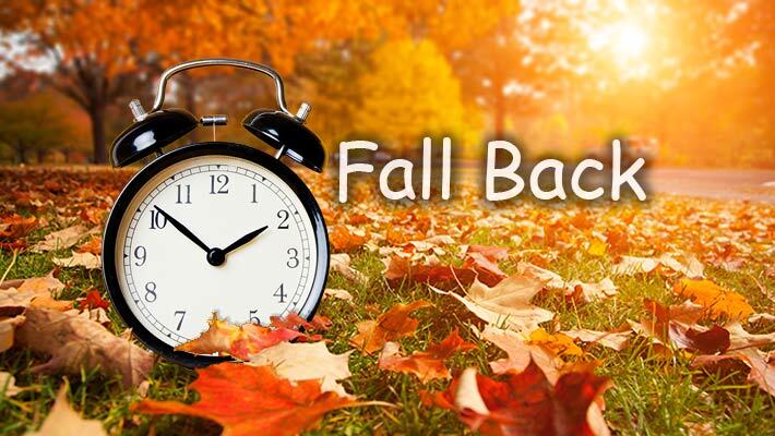 Fall Back with an alarm clock and leaves in the background.